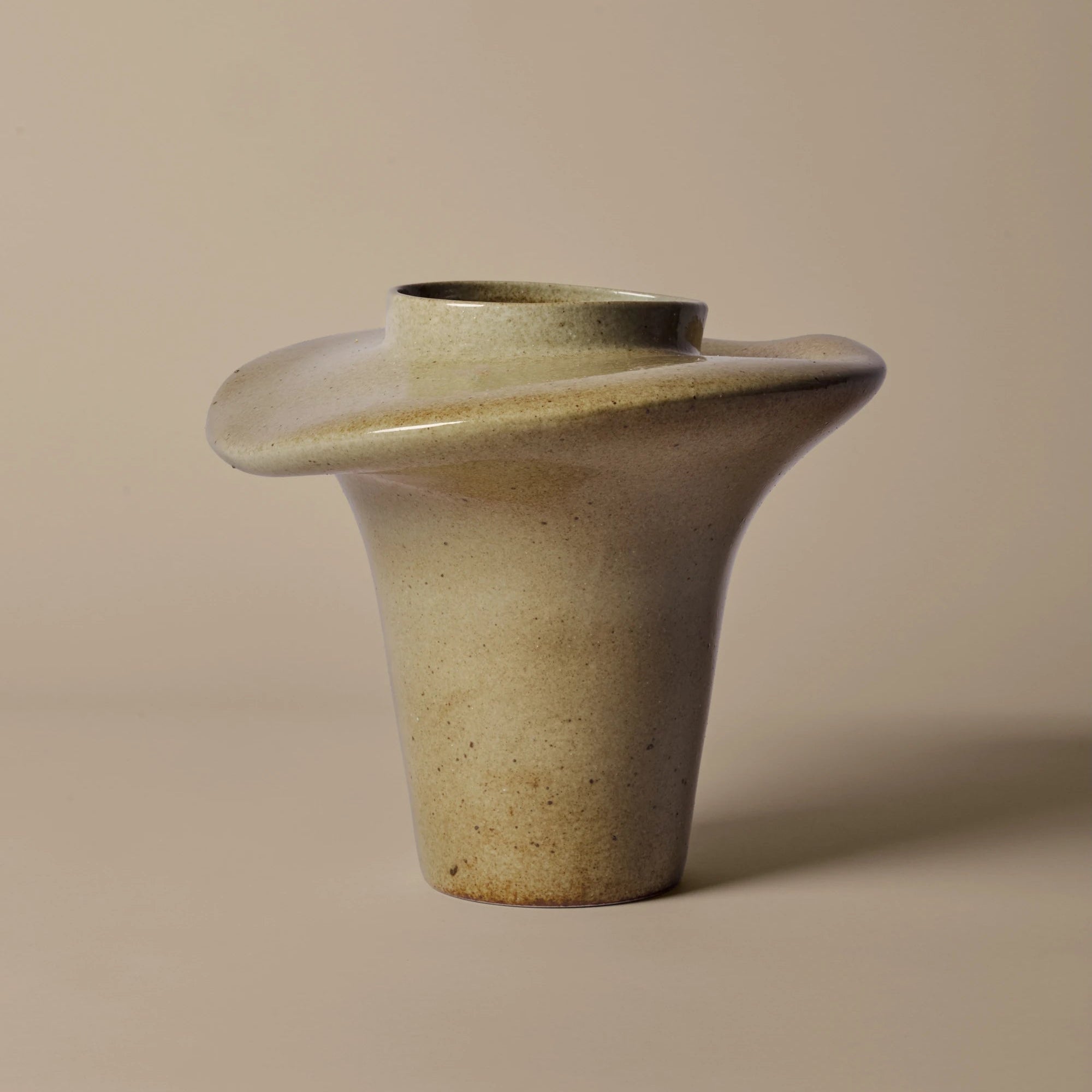 Cylindrical ceramic vase with a wide base and narrow top on a beige background