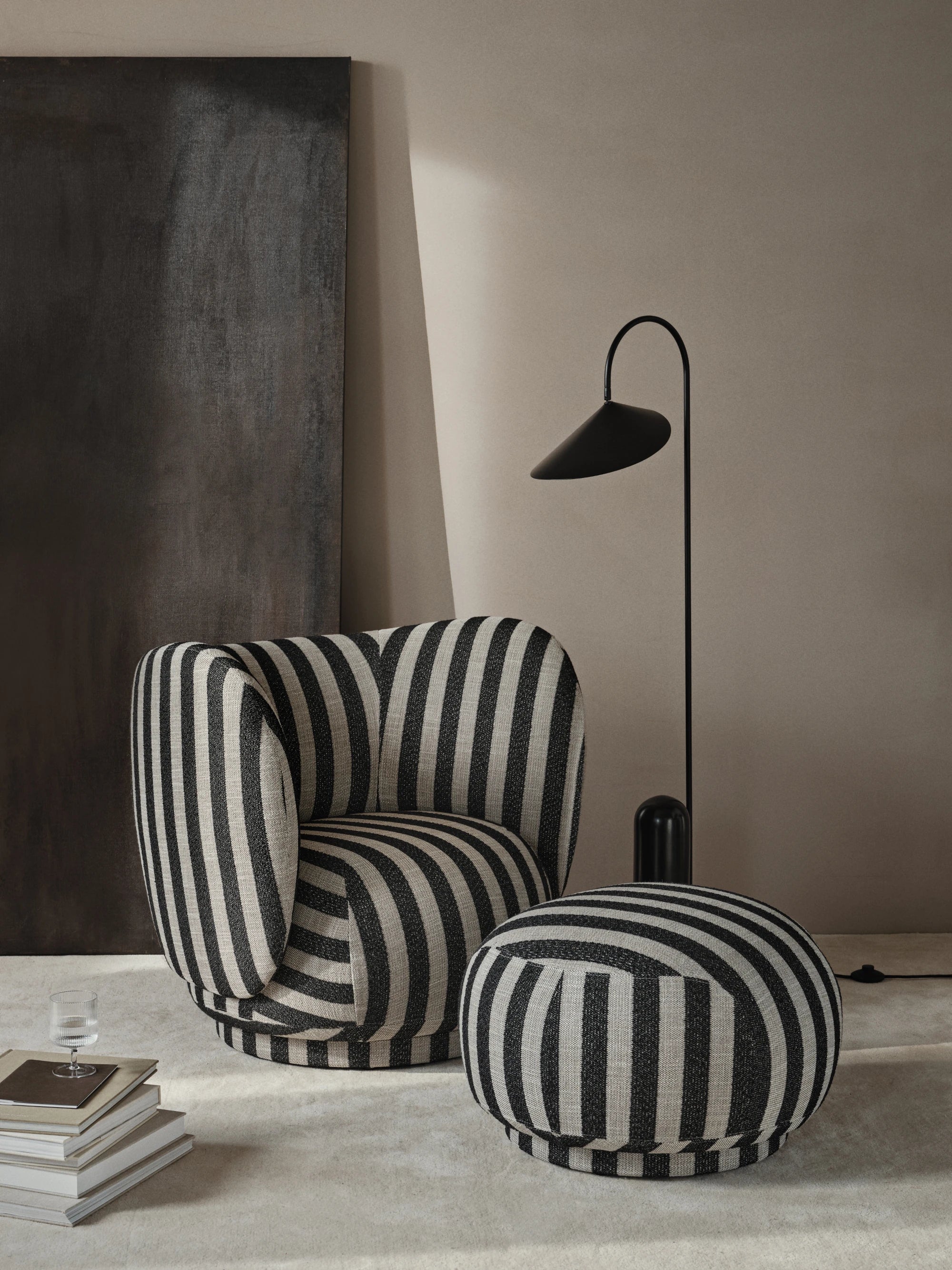 Ferm Living Rico Lounge Chair and foot stool in Louisiana fabric against a dark and beige wall with the Arum standing floor lamp