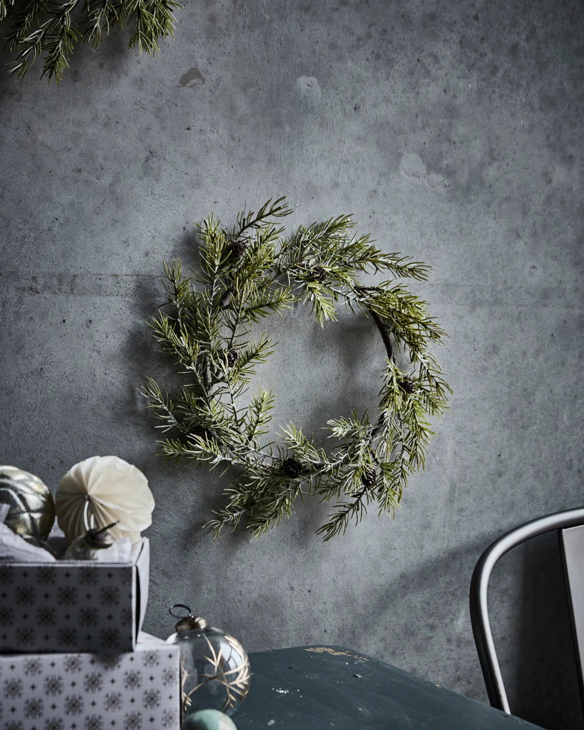 House Doctor 'Frost' Door Wreath - 35cm hanging from a textured grey wall with other ornaments to the left