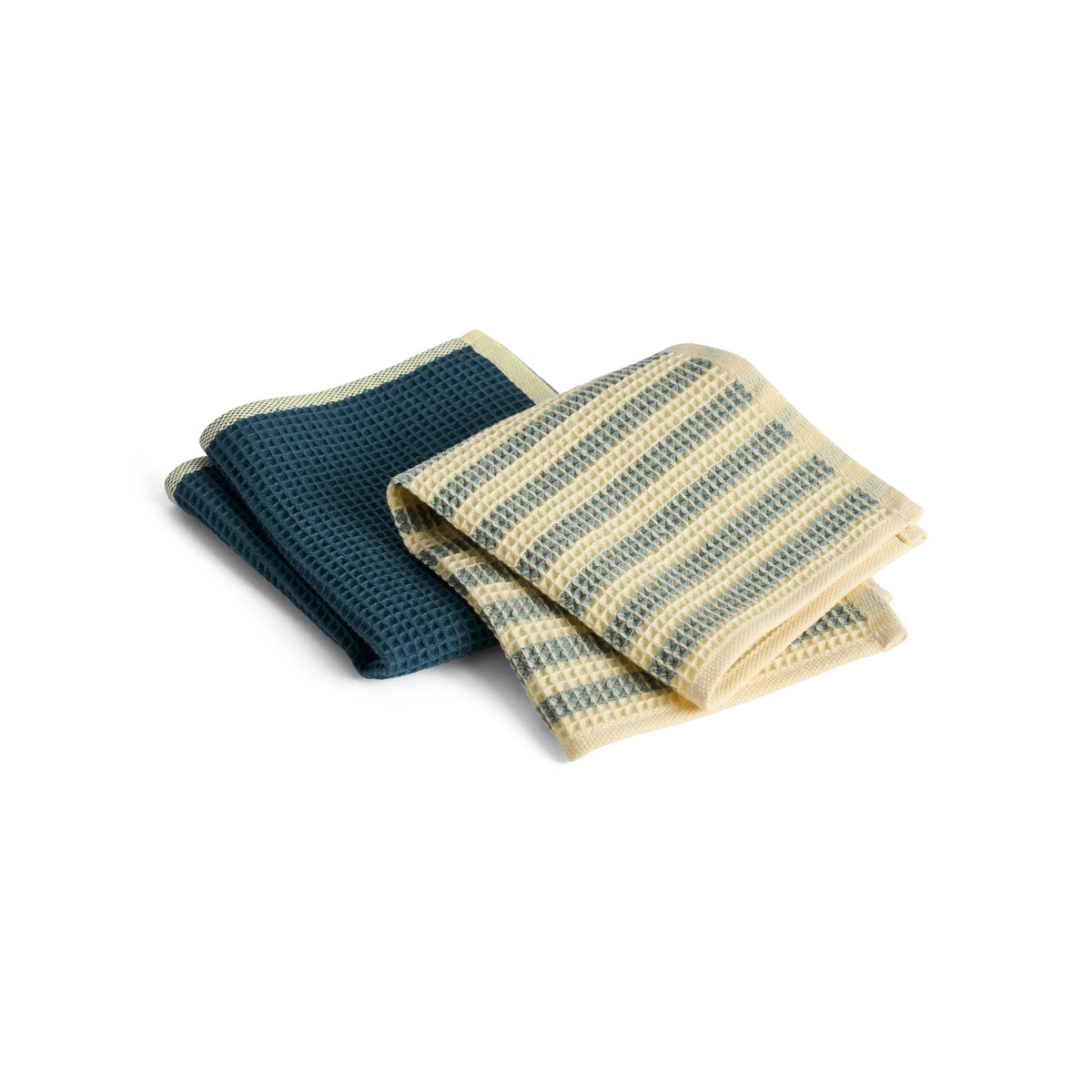 Two folded textured HAY Canteen wash cloths on a white background, one solid dark teal and one cream with horizontal teal stripes.