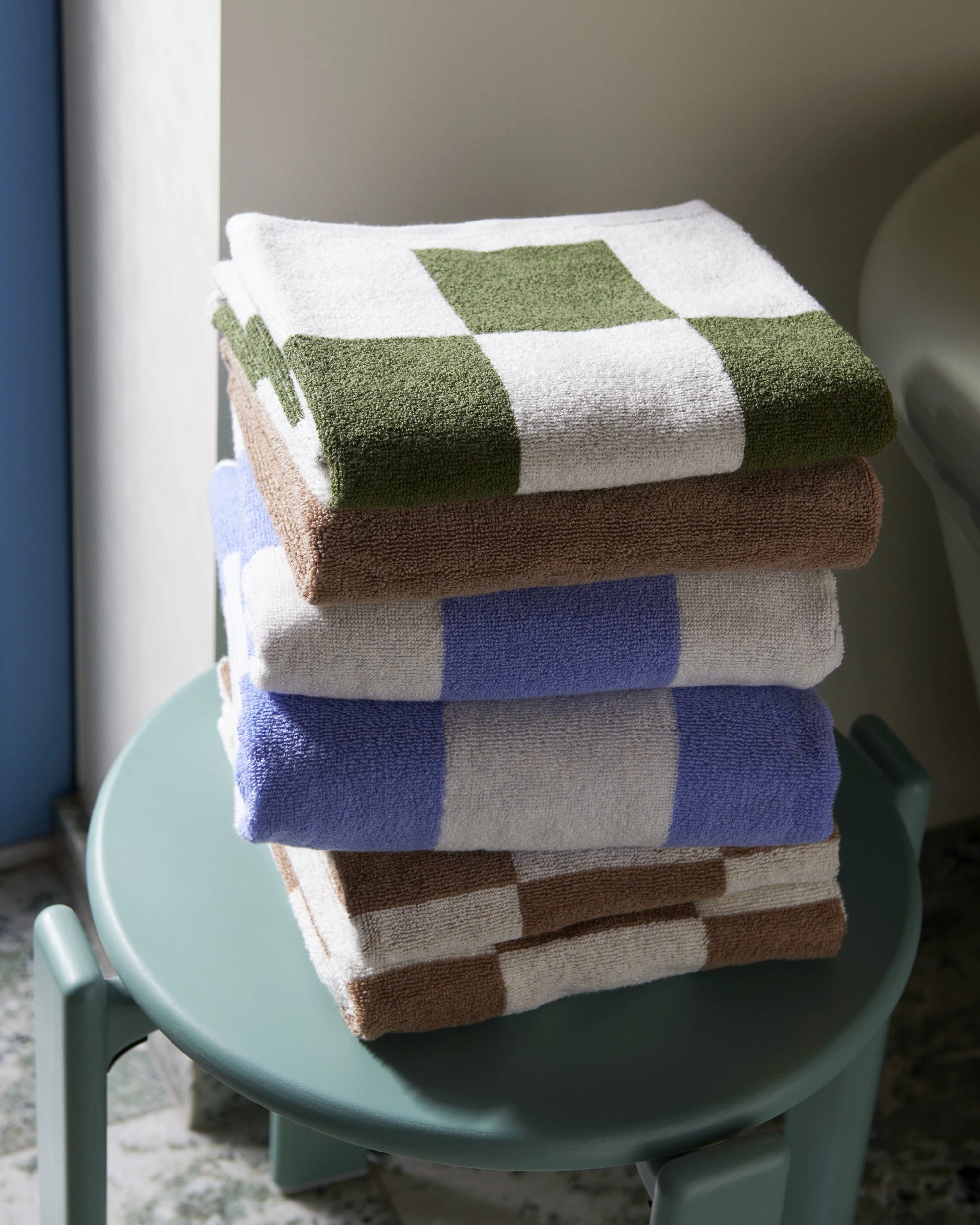 HAY Organic Cotton Check Wash Cloth stacked up on a blue stool