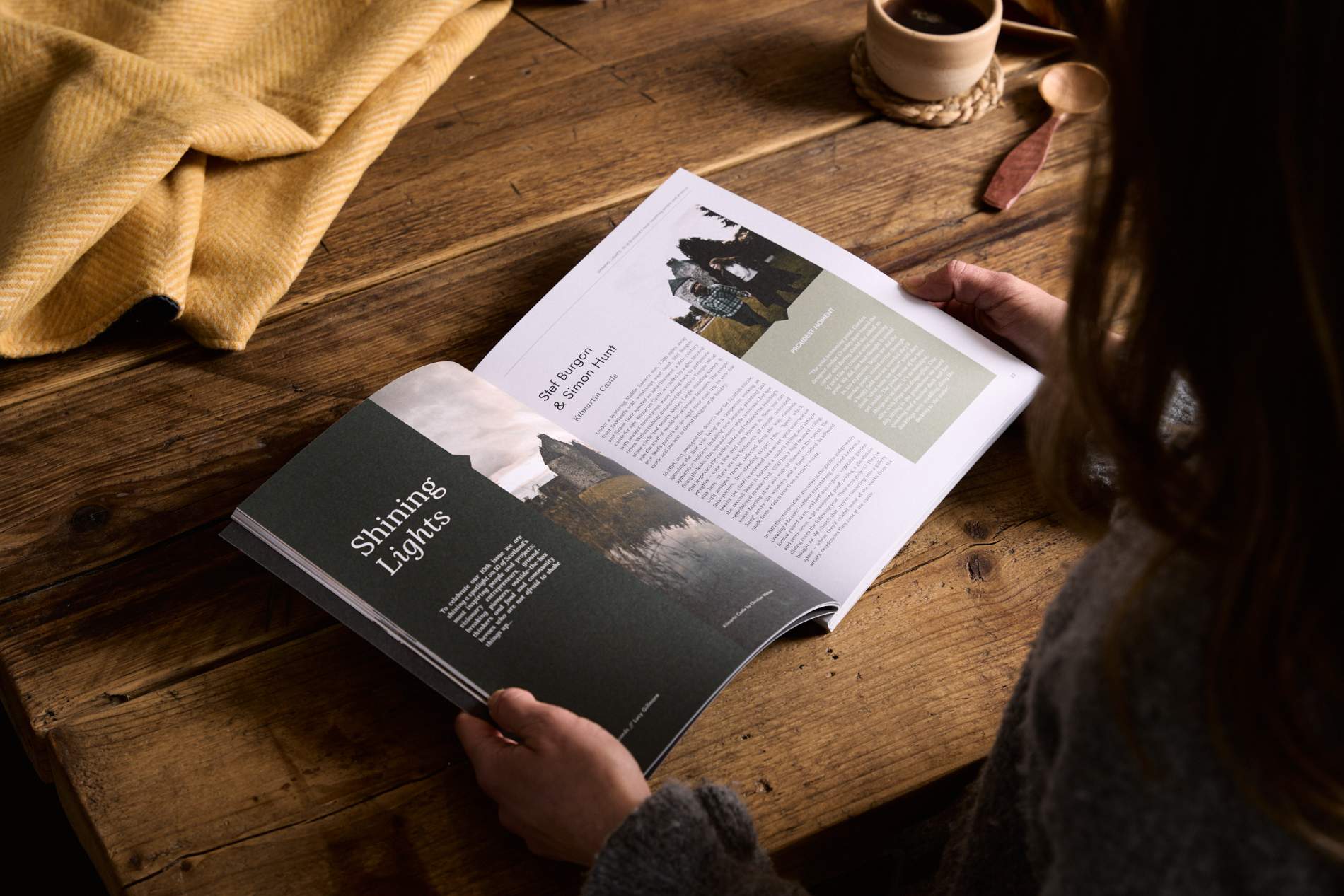 Hidden Scotland Magazine Issue 10 held open in hands on a wooden table at Lifestory Store