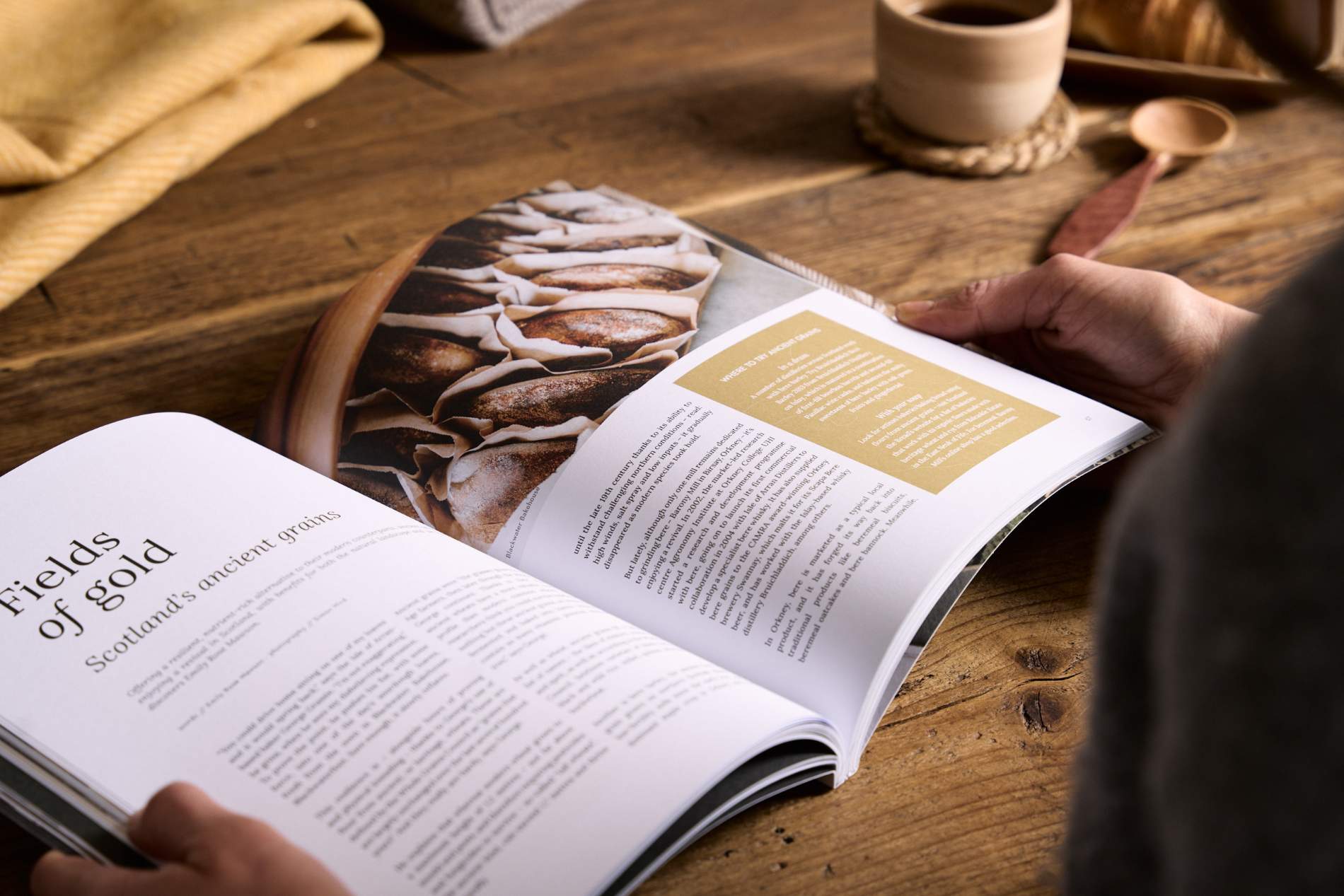 Hidden Scotland Magazine Issue 10 held open in hands on a wooden table at Lifestory Store