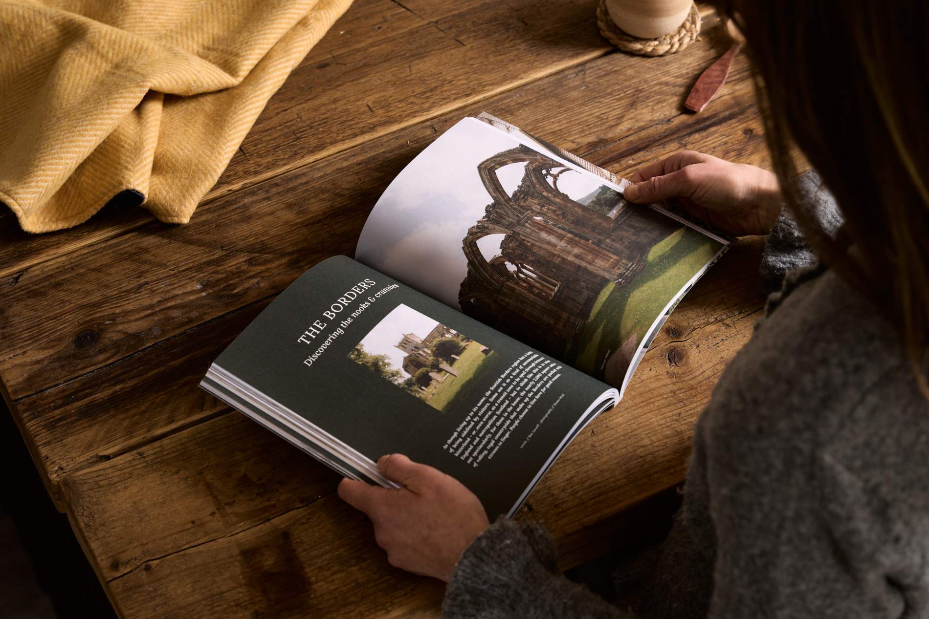 Hidden Scotland Magazine Issue 10 held open in hands on a wooden table at Lifestory Store