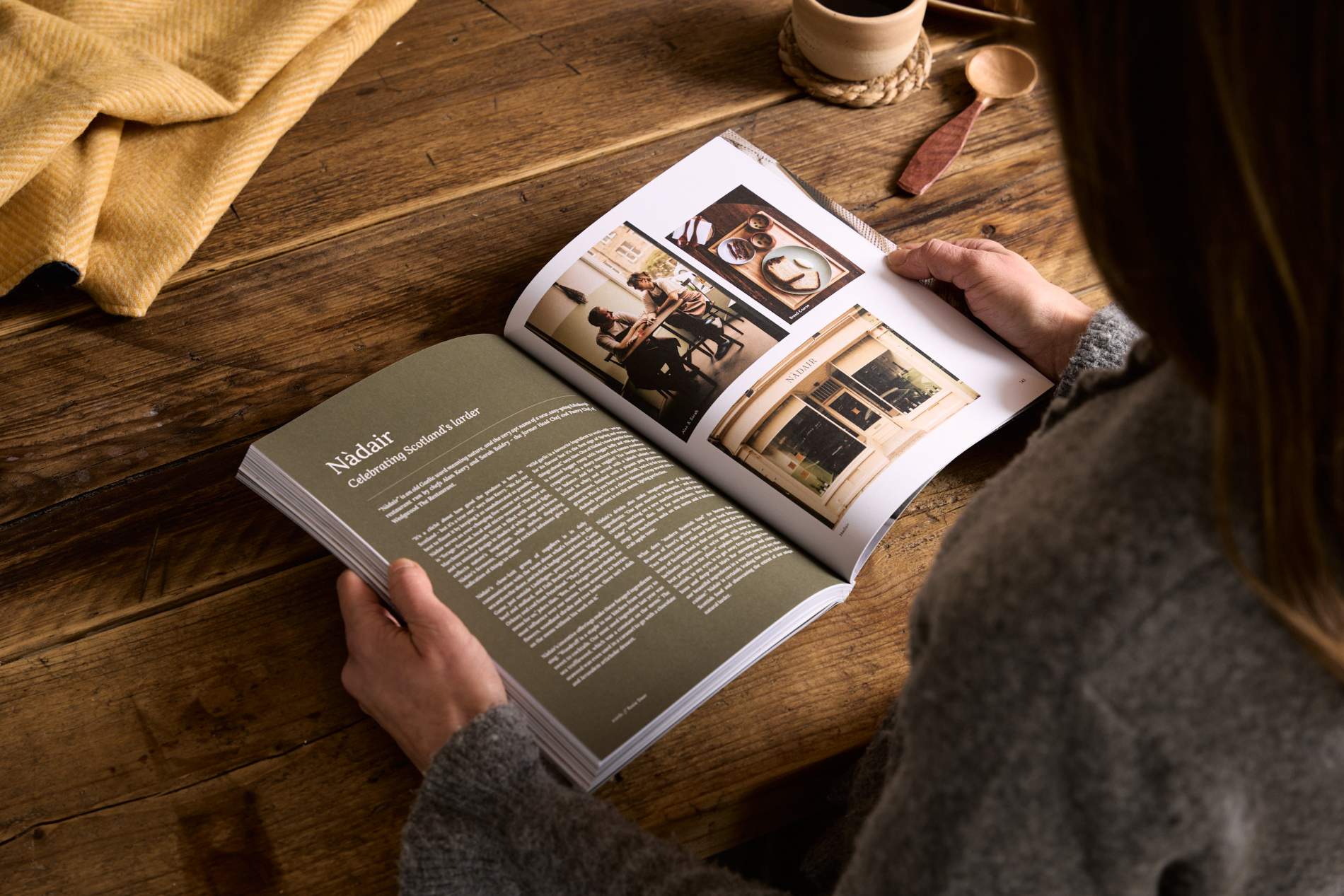 Hidden Scotland Magazine Issue 10 held open in hands on a wooden table at Lifestory Store