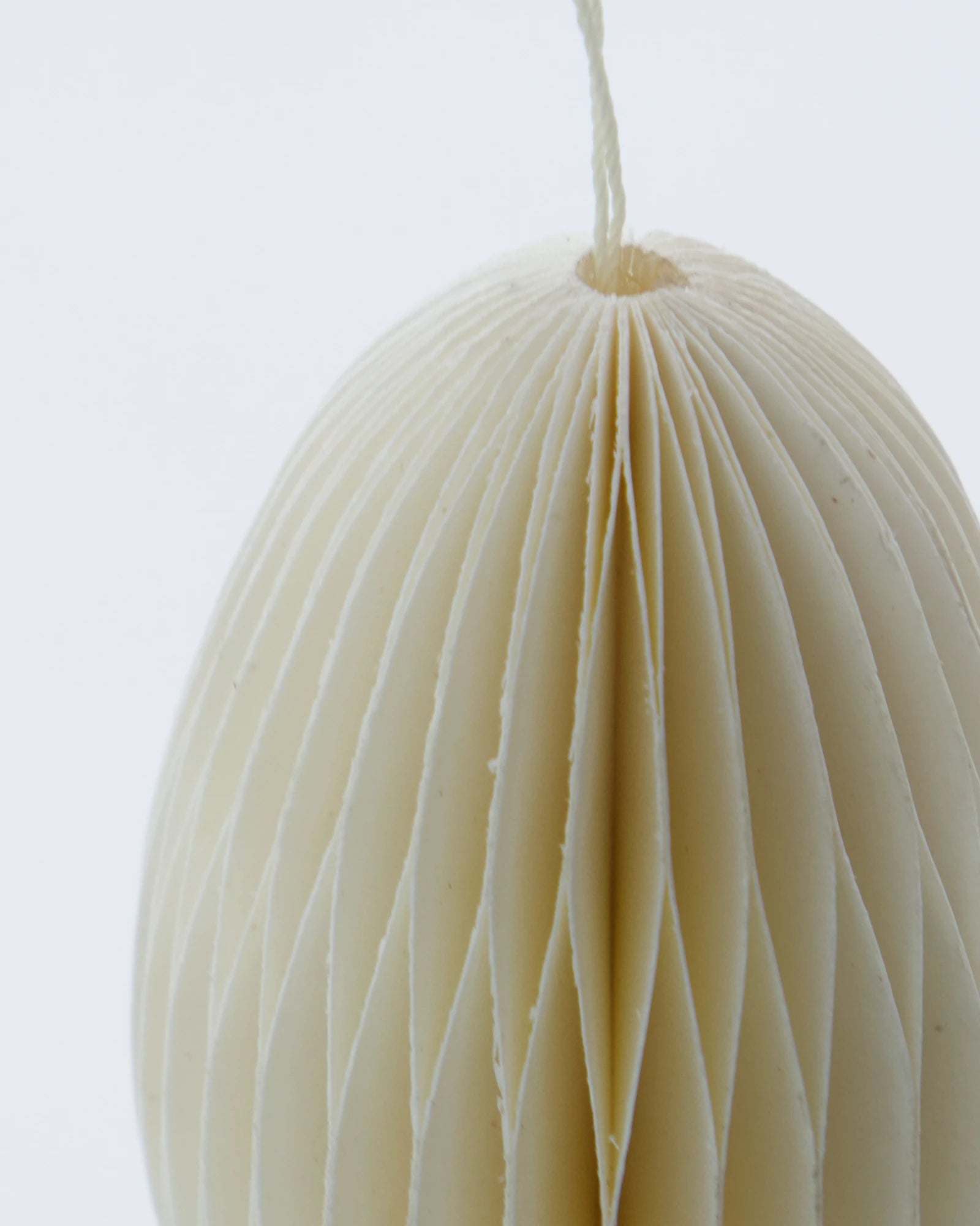 Close-up of a beige honeycomb paper egg ornament with a white background