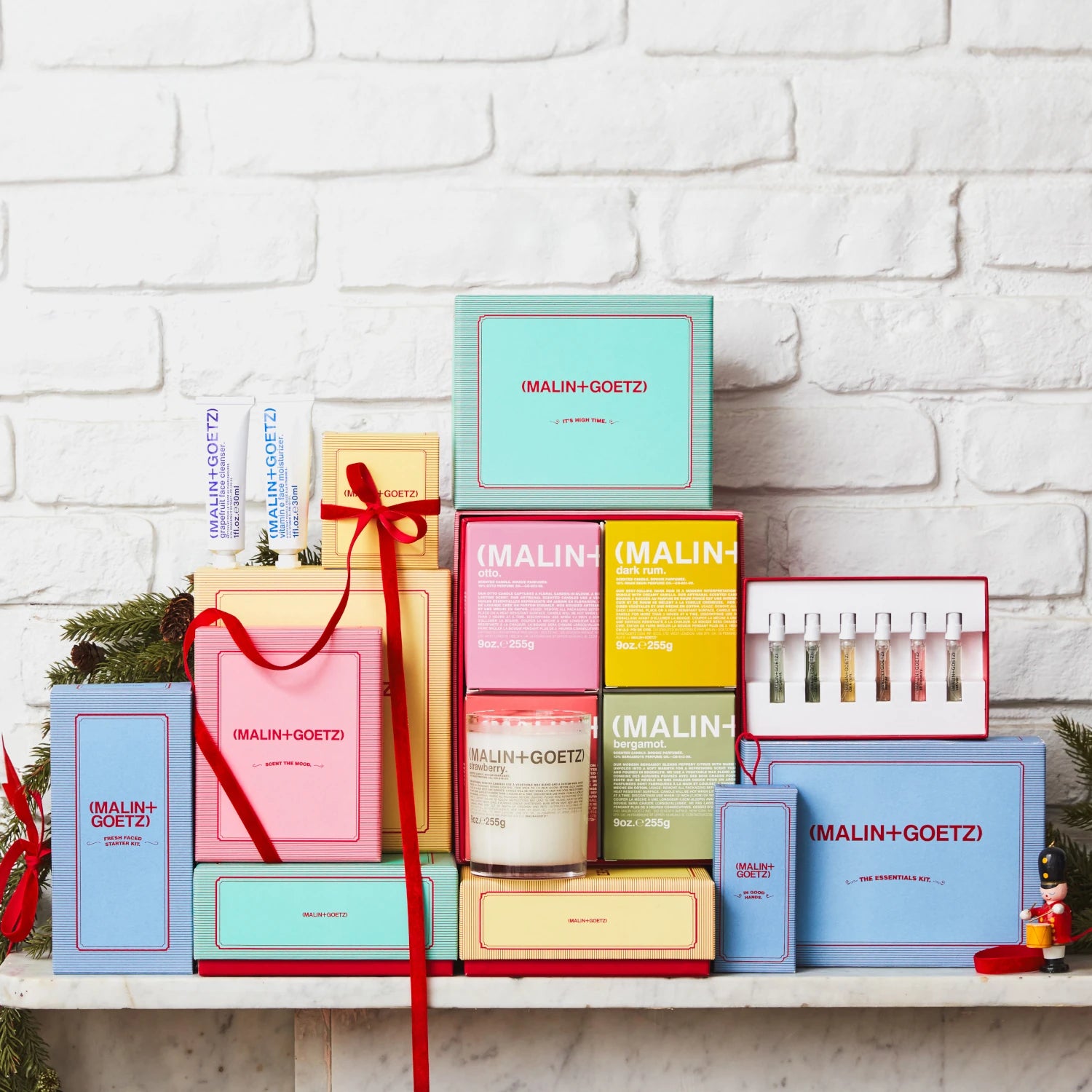 Malin and Goetz full 2024 gift set collection stacked up in front a white brick wall