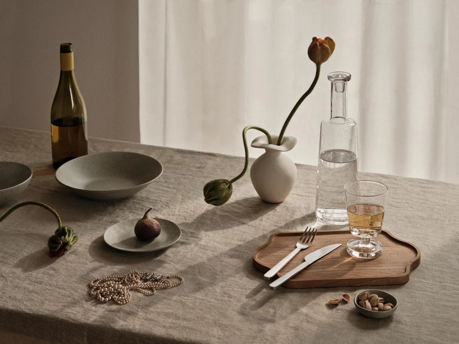 Broste Copenhagen Off-white Glazed Stoneware XS Florentina Vase with two single tulips on a table with table and flatware
