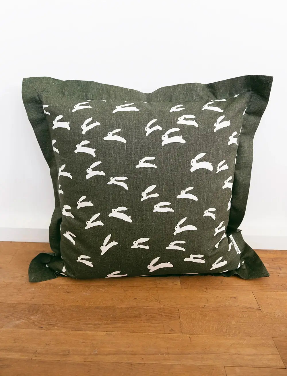 A square moss green cushion with playful white rabbit print by Fine Little Day