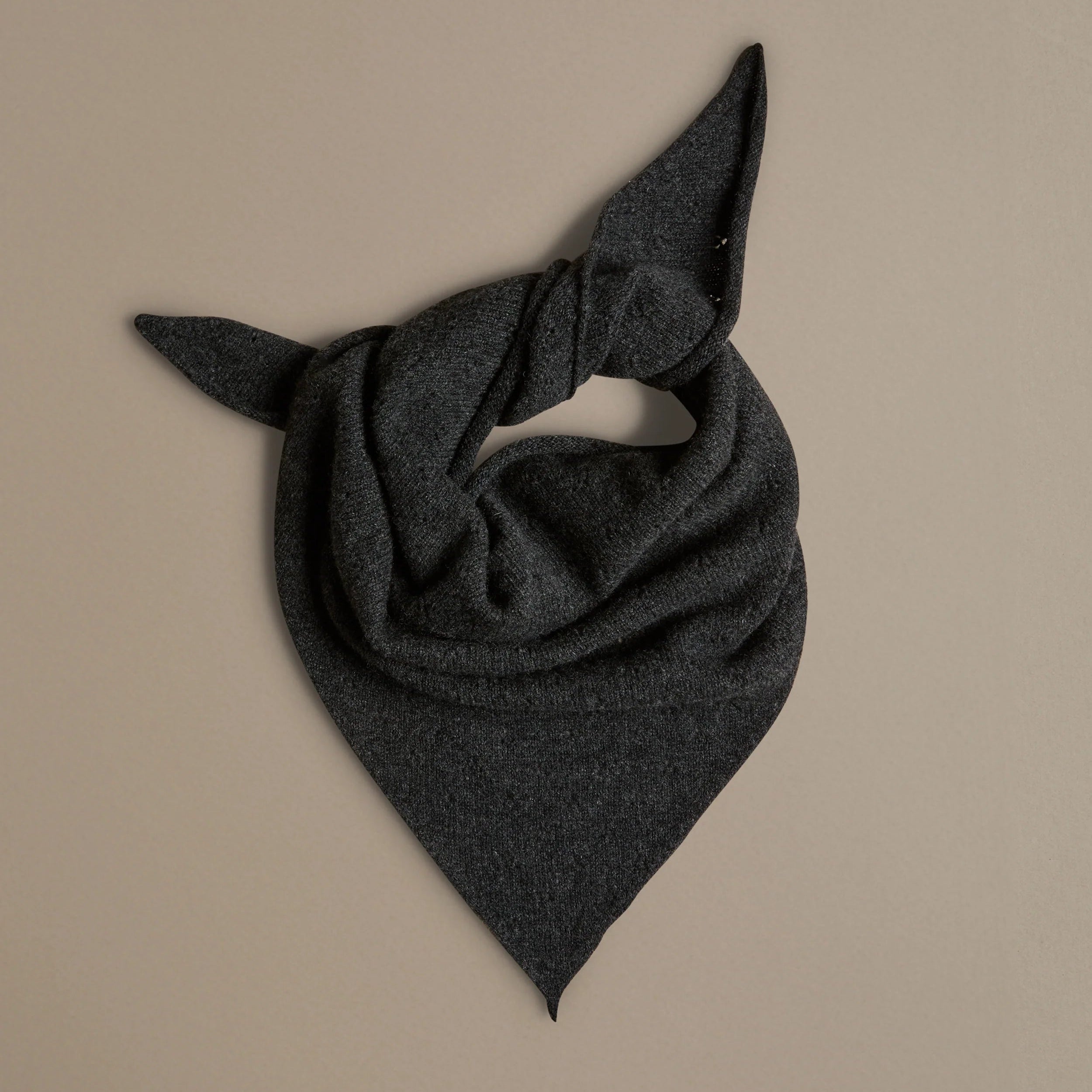 charcoal grey triangle scarf tied and laid on a beige background