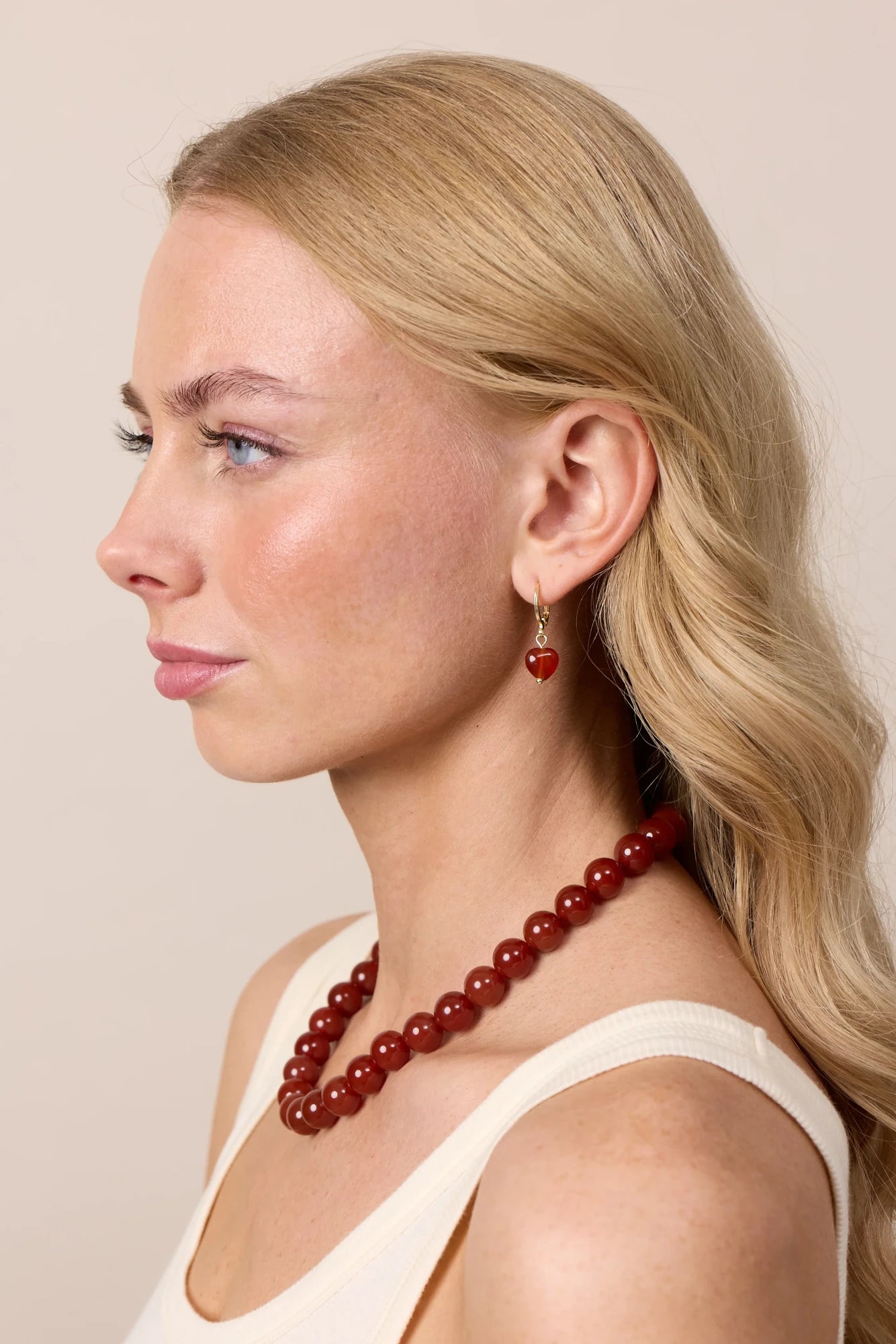 Woman wearing Soï Copenhagen Alma Red Jade heart earrings in 18k gold