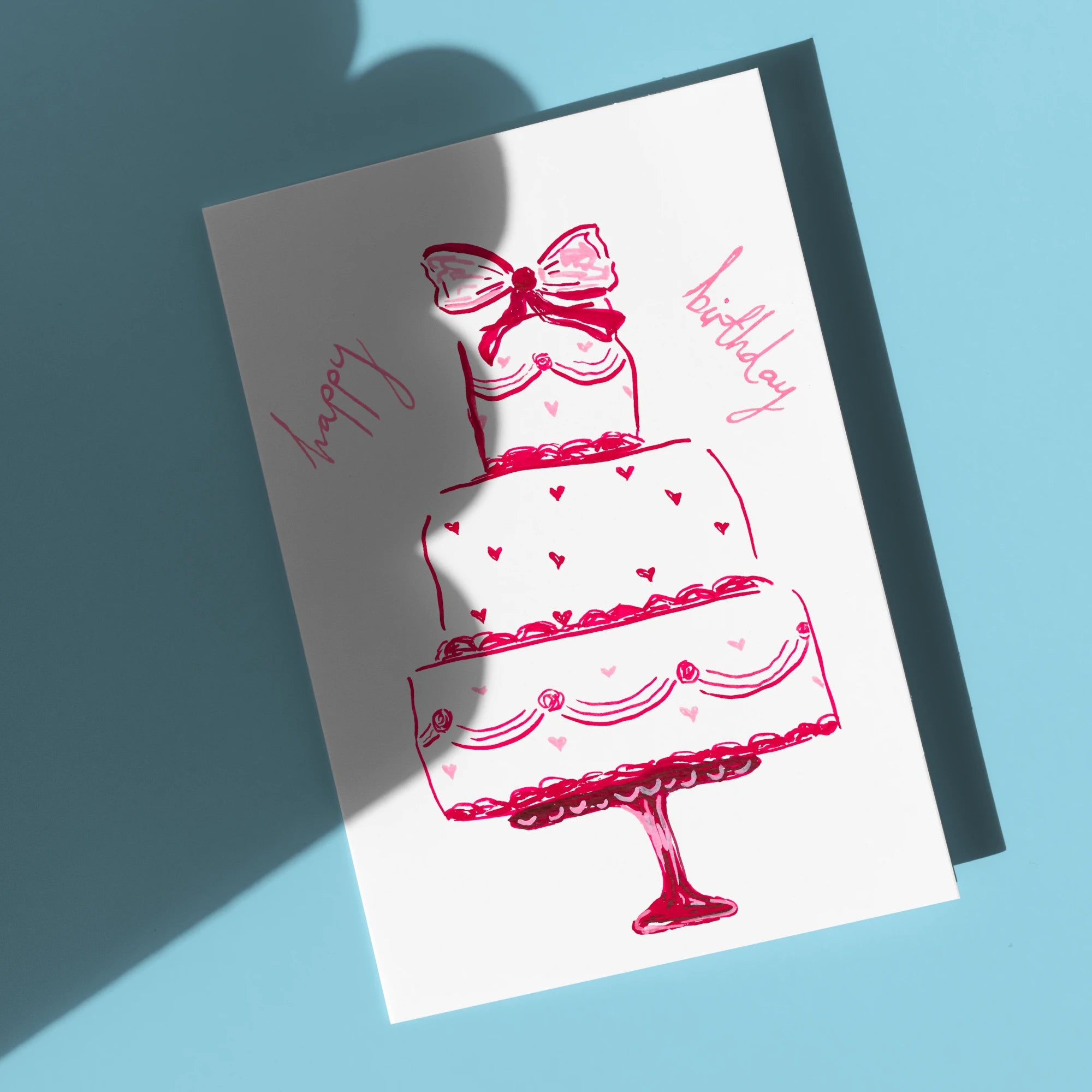 Happy Birthday Cake Card by Tecari Designs in front of a blue background with a wobbly shadow across it