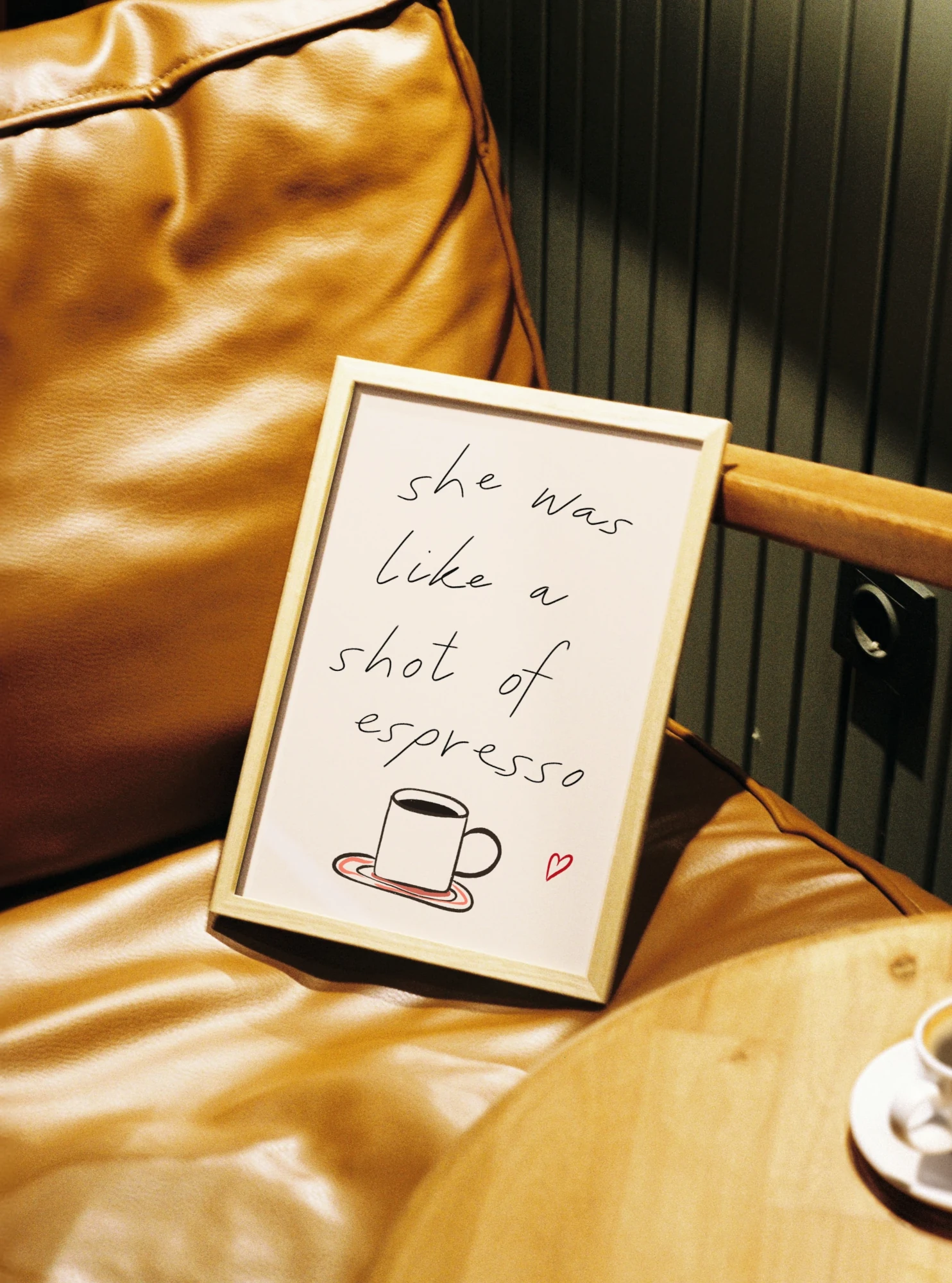 Framed picture by Tecari Designs with a quote about coffee on a wooden surface with a cup in the background