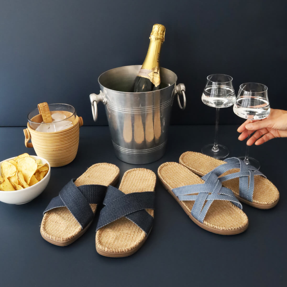 A party display featuring a champagne bottle and bucket with glasses and snacks next to two pairs of Shangies sandals