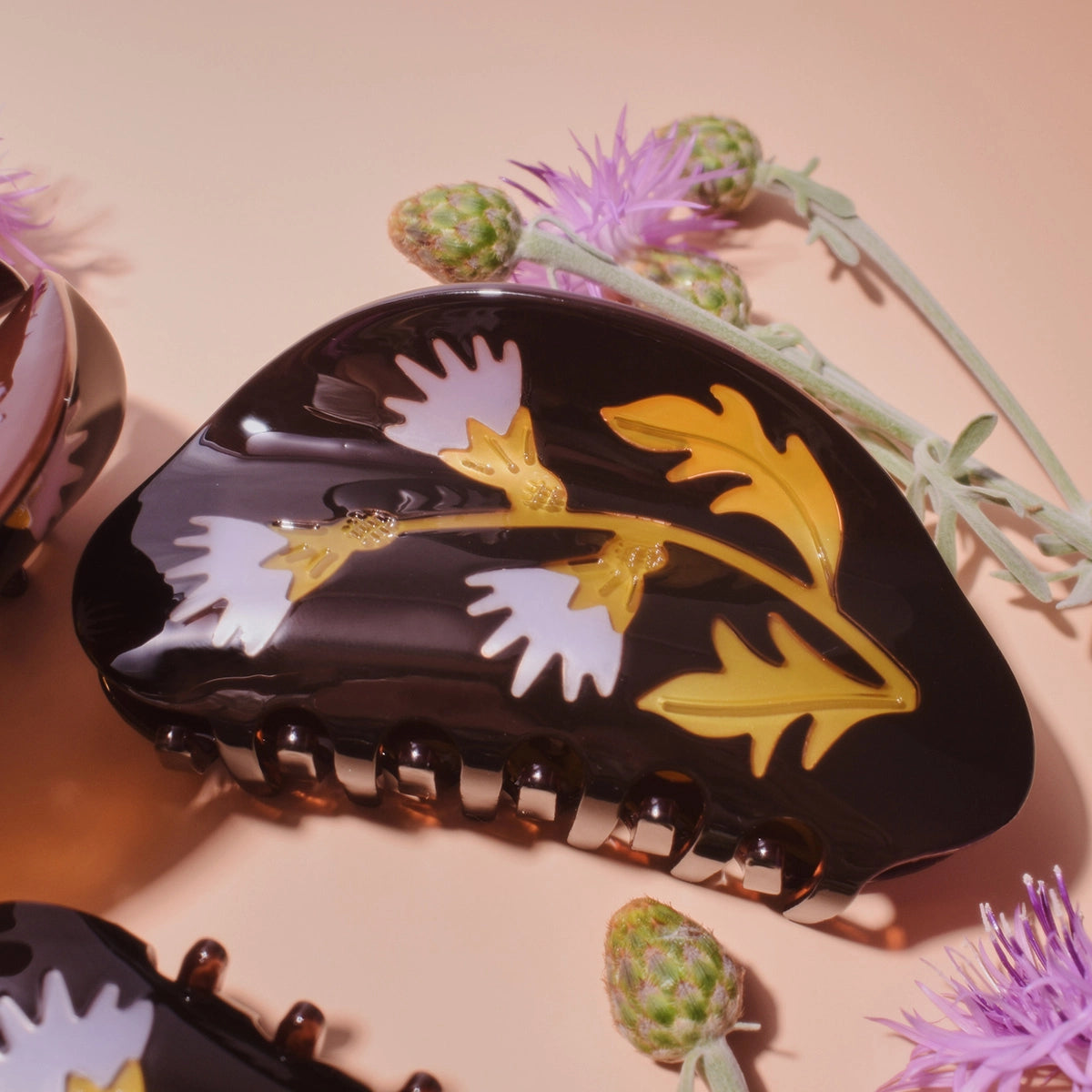 Winona Irene Milk Thistle Acetate Hair Claw on a pink surface surrounded by thistle flowers