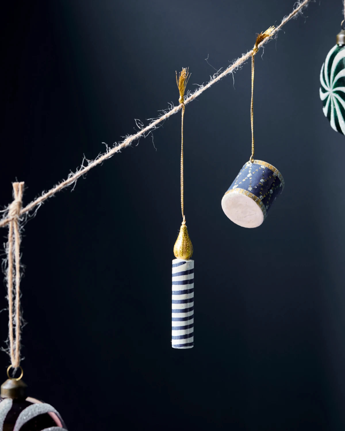 House Doctor Set of 3 Wooden Candle Hanging Ornaments with other ornaments hanging from twine against a dark background