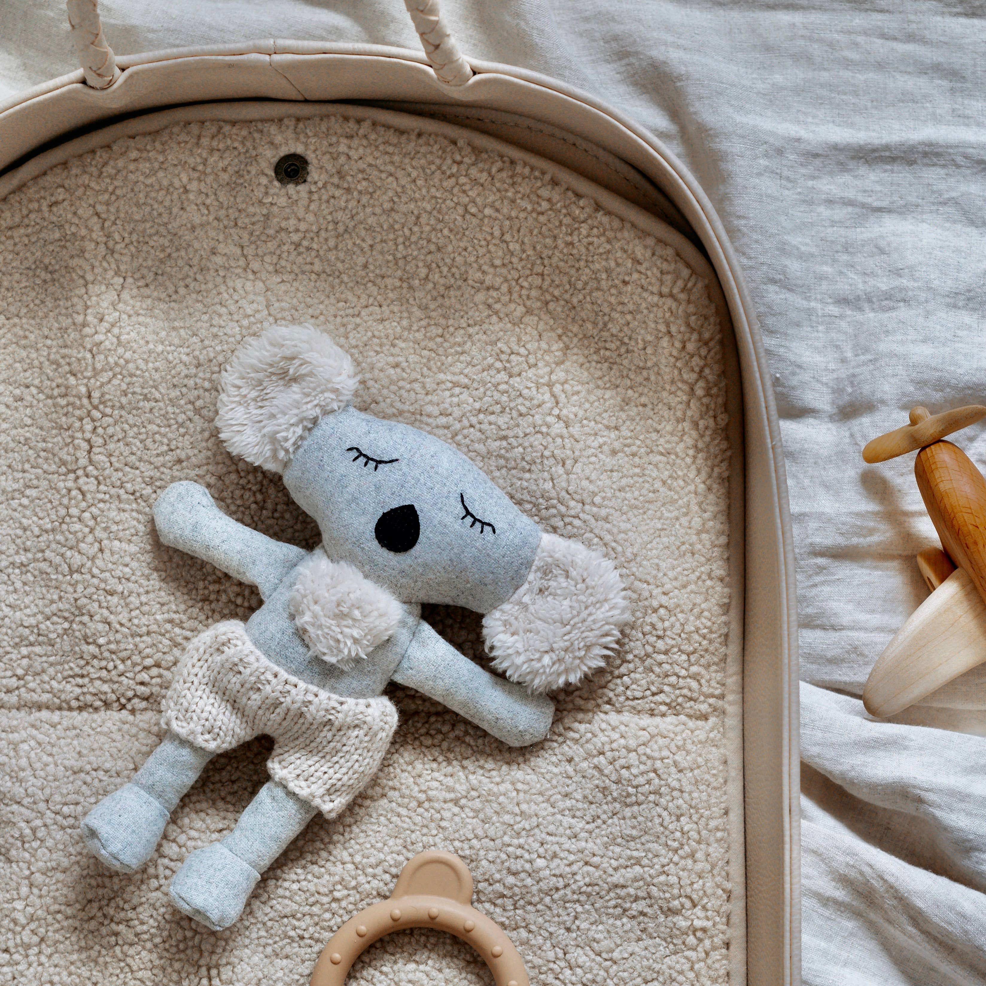 Plush toy koala in a crib with teething toys around