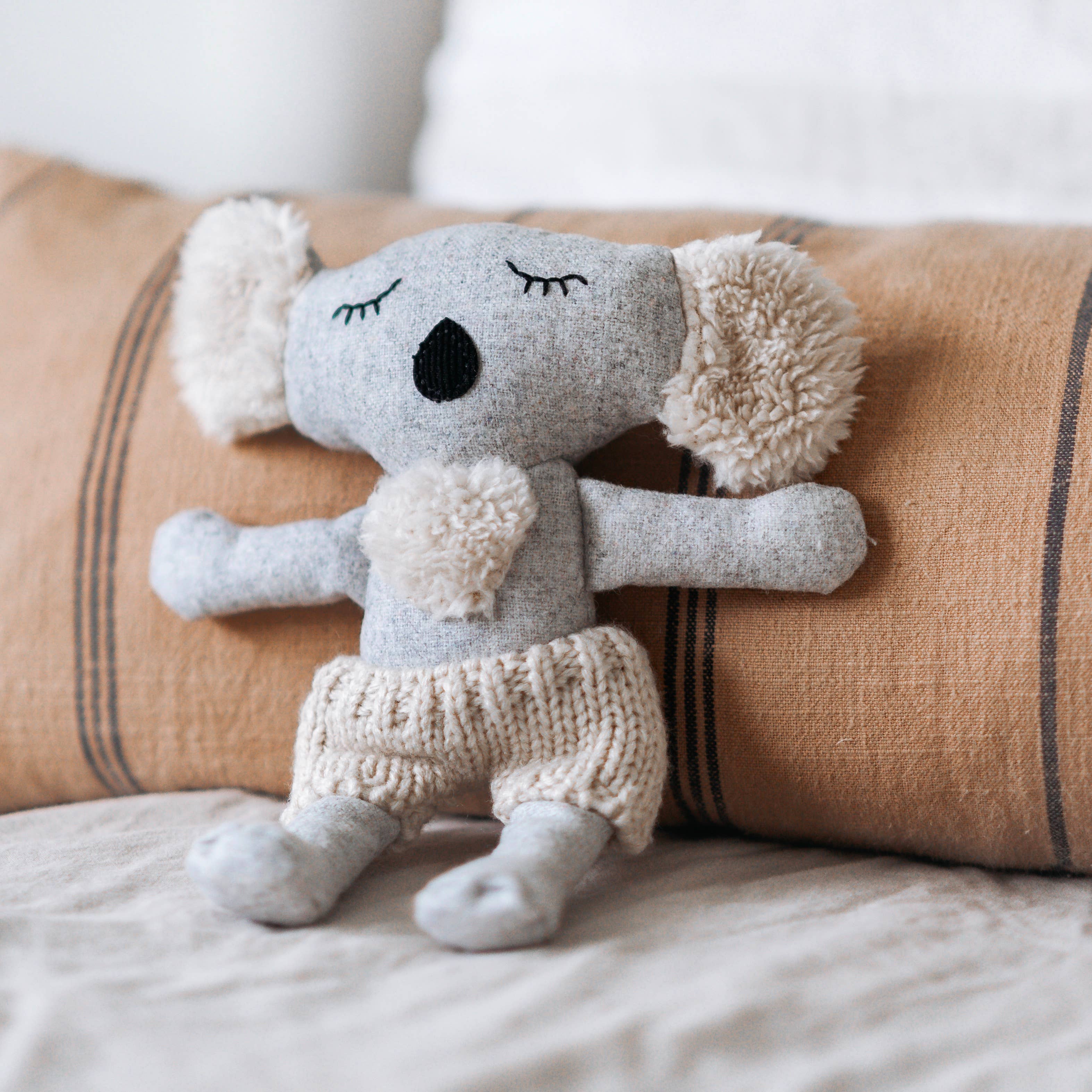 Plush toy koala in front of a beige pillow