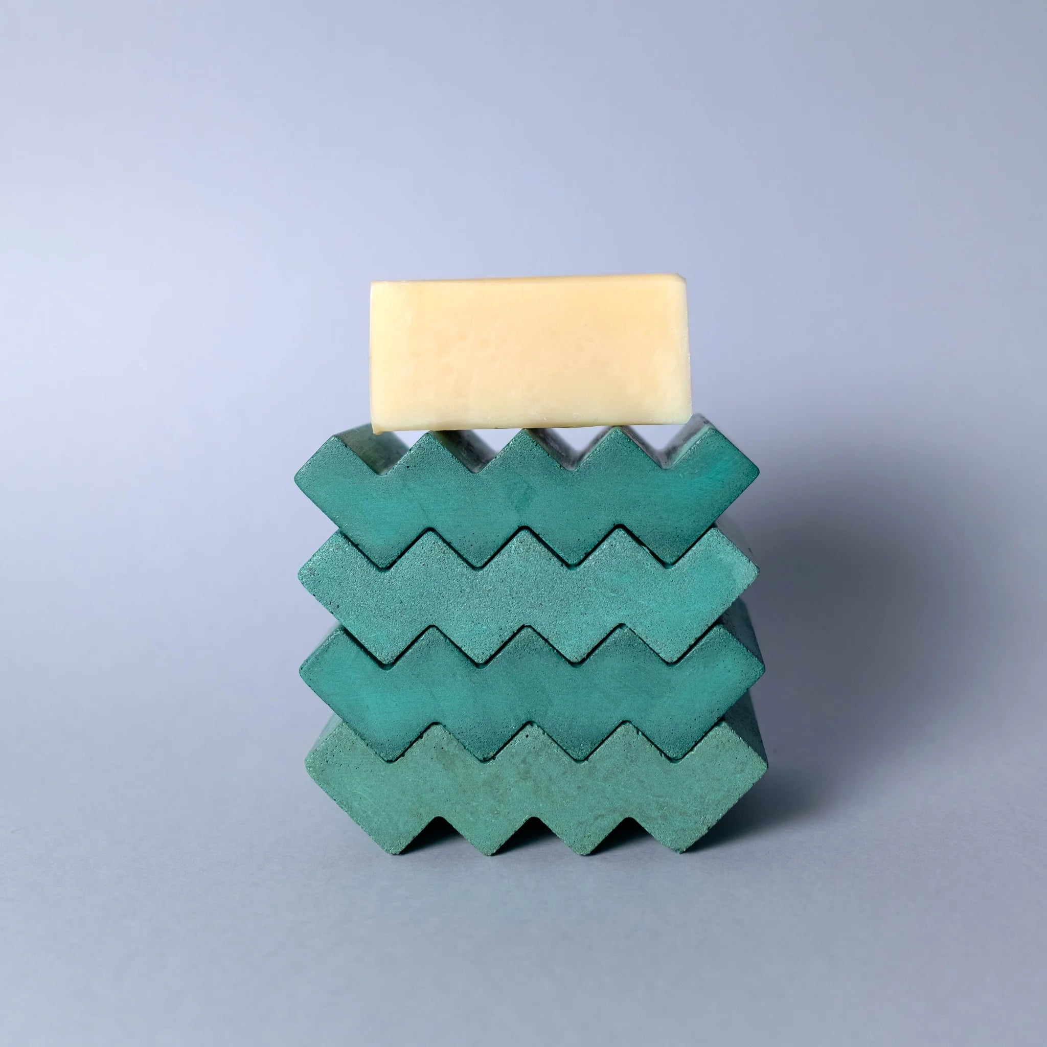 Stack of green soap dishes in zig zag shape with a soap on top
