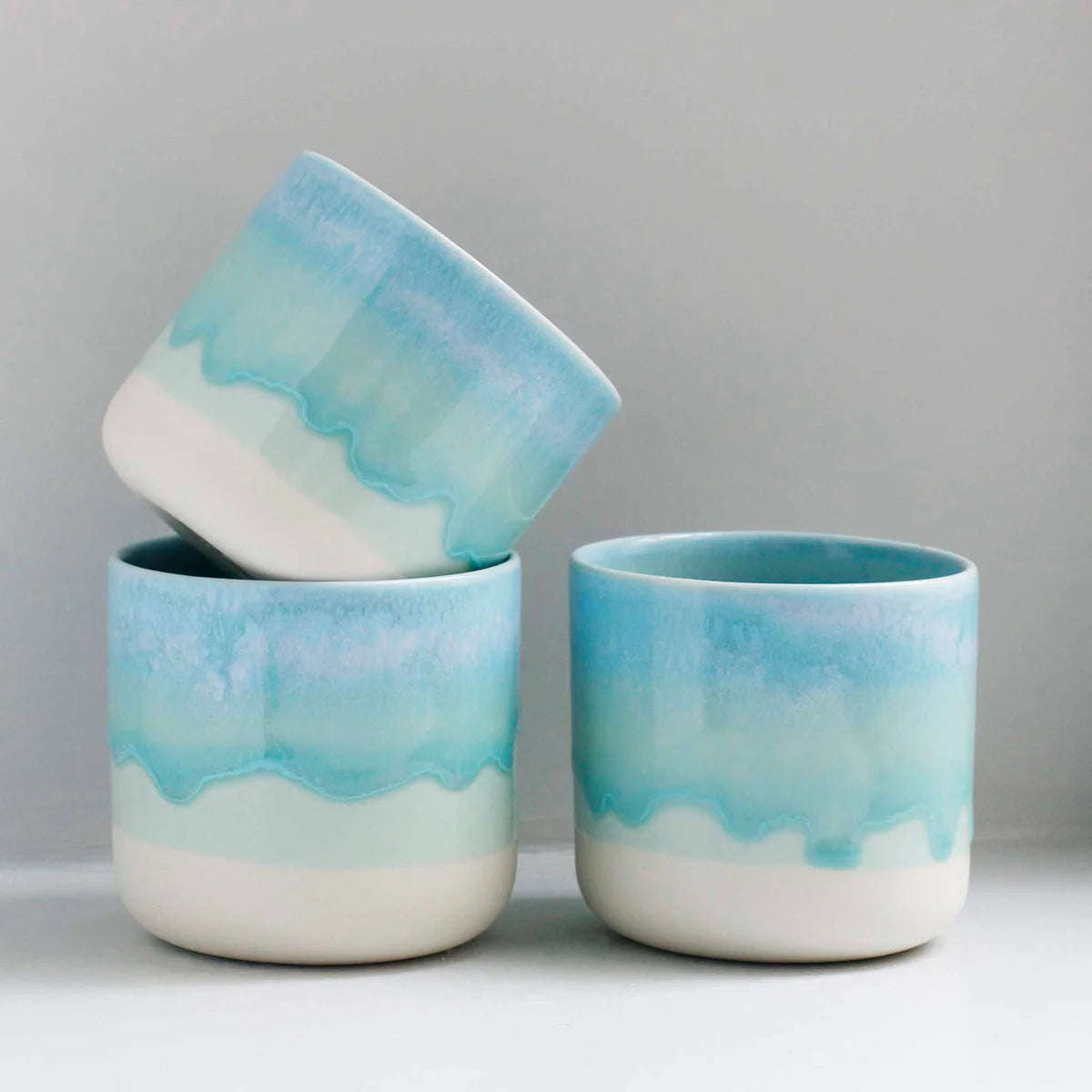 Three white, blue and aqua green handleless cups